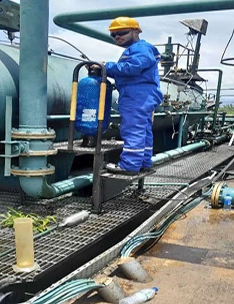 Corfluid field engineer in blue coveralls and hard hat at a wellsite separator